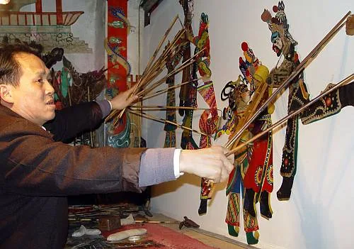 A puppet master performing several Chinese shadow puppets at once