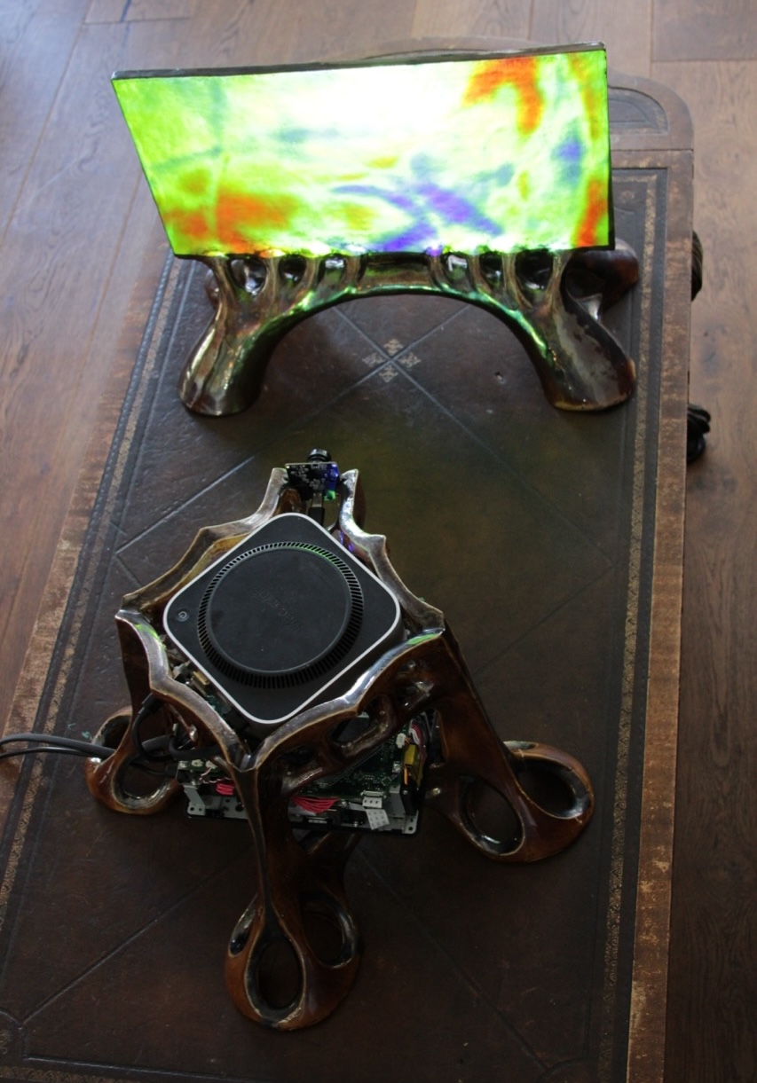 Overhead view of the glowing screen and the computer inside a four-legged ceramic shell