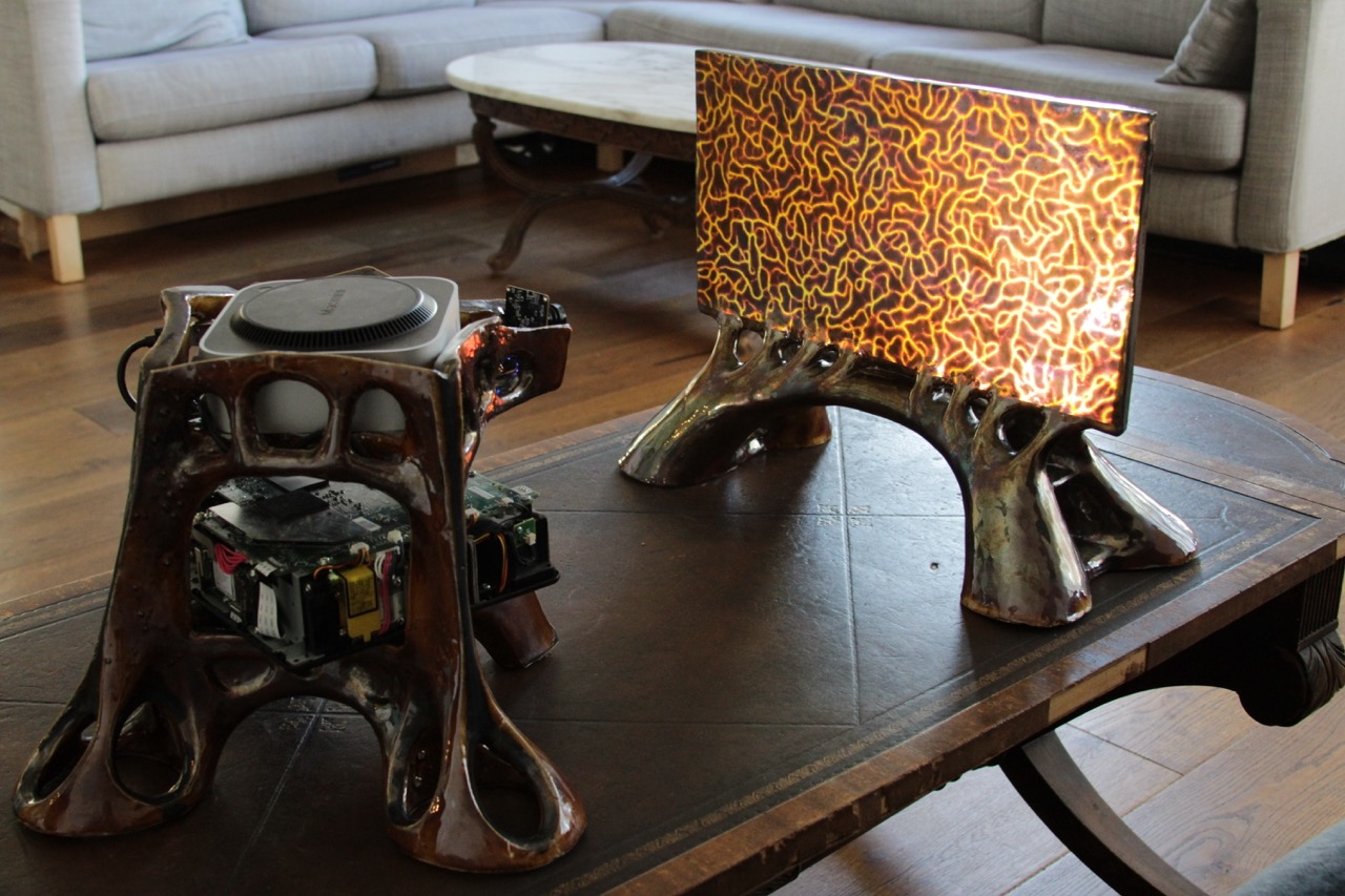 The screen showing an orange branching pattern beside its ceramic computer housing